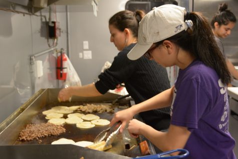 Laura Martinez (right) and sister Dulce Martinez (left) prepare food for an order. Laura Martinez owns a taco food truck with her husband and has used her business as a means to support not only herself but her family as well.