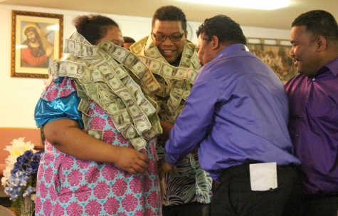 Pastor Alfred Alfred stands with a Marshallese woman during the United Church of Christ Sunday service on April 2, where men and women approach the two with taped dollar bills to place around their necks. The tradition is symbolic for Alfreds reputation within the community.