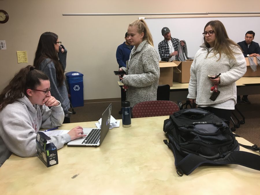 President Avery Brant passes out t-shirts to members of the medical Global Brigades on the eve of their fundraiser Crimson and Caffeine, Wednesday, Nov. 29.