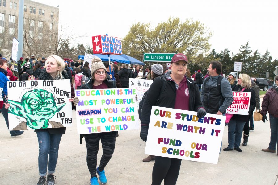 Three+demonstrators+hold+signs+in+support+of+the+Oklahoma+Teacher+Walkout+on+April+4.+Attendees+marched+in+solidarity+for+an+increase+in+funding+for+public+education.+