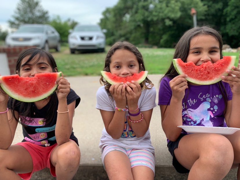 Kim Duncan’s three adopted daughters, from left, Shalyn, Shyanne and Shelbi, sit smiling with their watermelon in the summer heat. (Photo provided)
